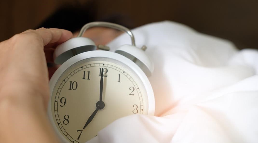  A person waking up in the morning with an alarm clock with the intention to have a healthy morning routine including breakfast, stretching, meditation and planning.